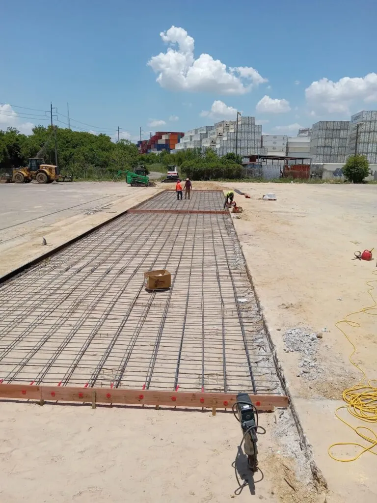 Workers preparing reinforcement for a concrete slab at an industrial construction site.