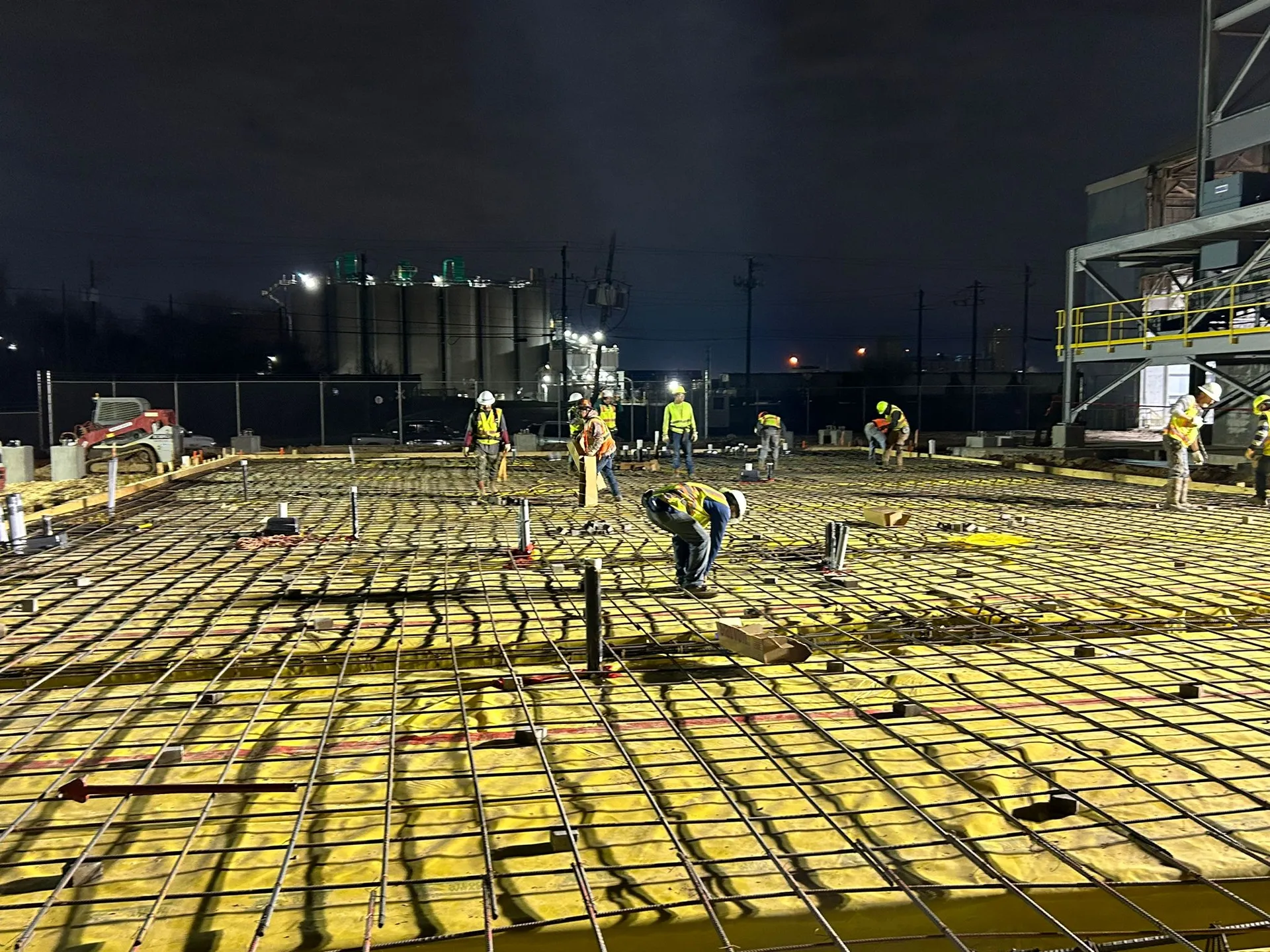 Concrete crew preparing a reinforced slab during a nighttime pour.