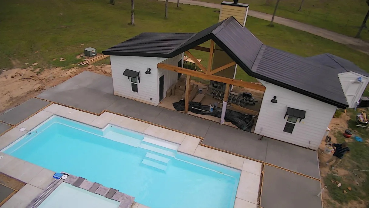Aerial view of a concrete pool area and adjacent structure under construction.
